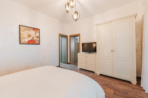 a white bedroom with a bed and a tv at Vila Anisoara in Predeal
