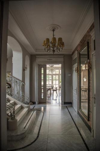 a hallway with a staircase and a chandelier at Palac i Loft Ojrzanów in Ojrzanów