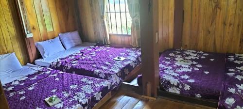 two beds in a room with purple sheets at Nam Pé Tày Homestay - View hồ Ba Bể in Bak Kan