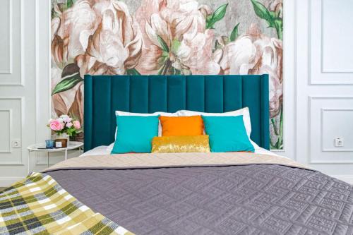 a bed with a blue headboard and colorful pillows at Medina Central Loft- 118 in Astana