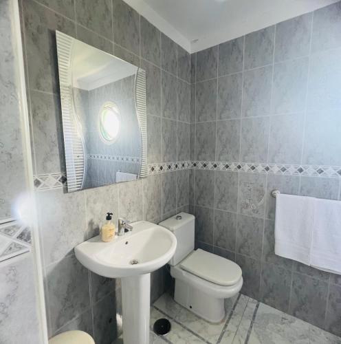 a bathroom with a sink and a toilet and a mirror at The Cozy Palm in Playa de las Americas