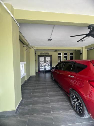 a red car parked in front of a garage at Rizqi Homestay Pasir Mas in Pasir Mas