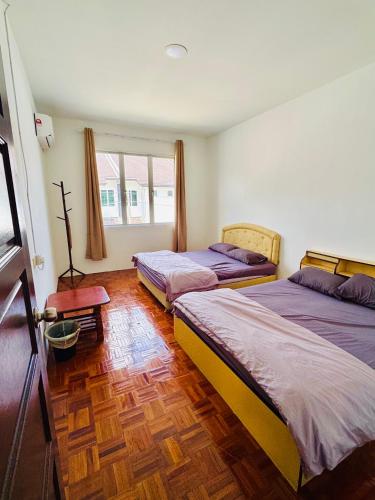 a bedroom with two beds and a wooden floor at HmHome-five in Sibu
