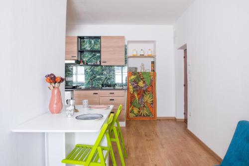 a kitchen with a white table and green chairs at B.I.C. (bnb in centro) in Sassari