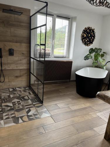 a bathroom with a tub and wooden floors at Villa 170m2 avec piscine , sauna , jacuzzi , terrain de petanque in Nompatelize