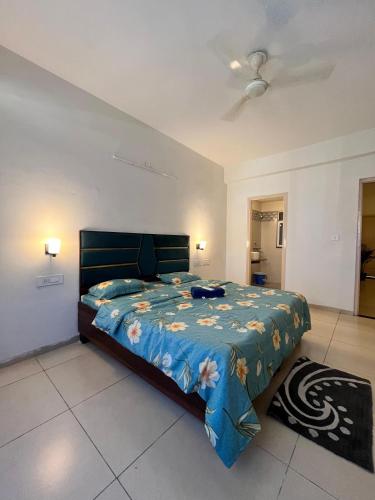 a bedroom with a bed with a blue comforter at 3BHK Cozy Apartment in Zirakpur