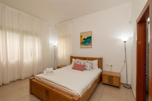 a bedroom with a bed with white sheets and two lamps at וילת נופש המלך שלמה in Wadi Keren