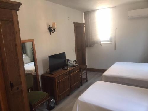 a hotel room with two beds and a television at Villa Pietra in Ayvalık