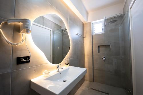 a bathroom with a sink and a shower and a mirror at Diamond Central Boutique Hotel in Sarandë