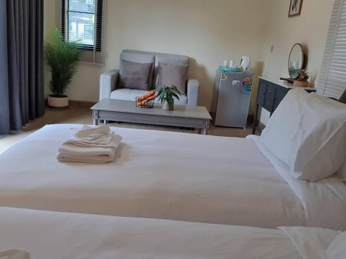 a bedroom with a large white bed and a couch at Nordika Hill in Pak Chong