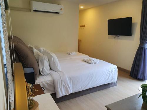 a bedroom with a white bed and a flat screen tv at Nordika Hill in Pak Chong