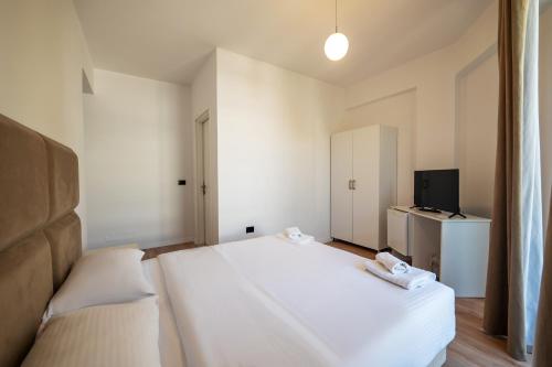 a bedroom with a large white bed and a television at Diamond Central Boutique Hotel in Sarandë