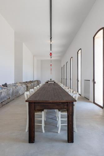 a long wooden table in a room with white chairs at Masseria LOGGIA PUCCI in Torre Chianca