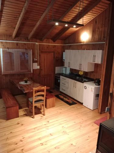 a kitchen with wooden floors and a table and a chair at Cabañas Arte Patagonia in Puyehue