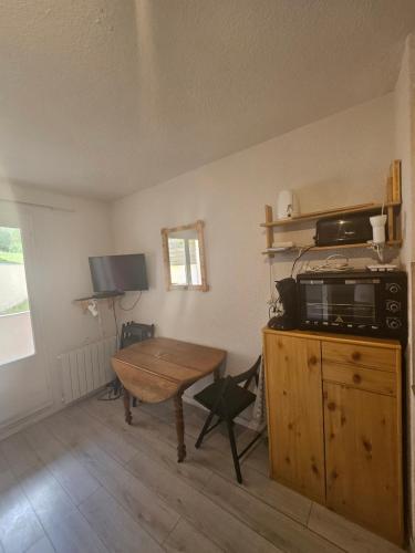 - un salon avec une table et un four micro-ondes dans l'établissement studio a la montagne, à La Foux