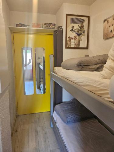 une chambre avec deux lits superposés et une porte jaune dans l'établissement studio a la montagne, à La Foux