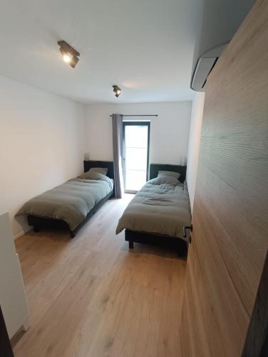 two beds in a room with white walls and wooden floors at Franco'gîte in Francorchamps