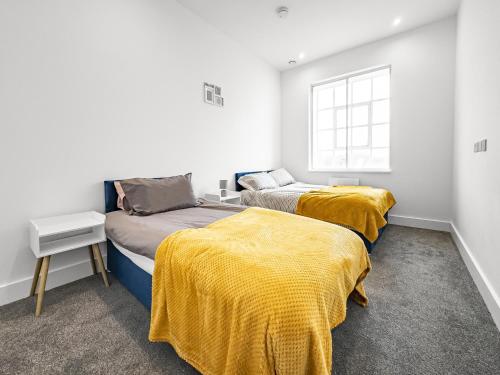 two beds in a room with yellow blankets at Bright & Cozy in Chelmsford in Chelmsford