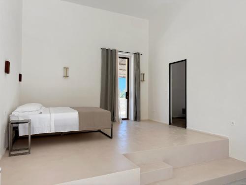 a white bedroom with a bed and a mirror at Masseria LOGGIA PUCCI in Torre Chianca