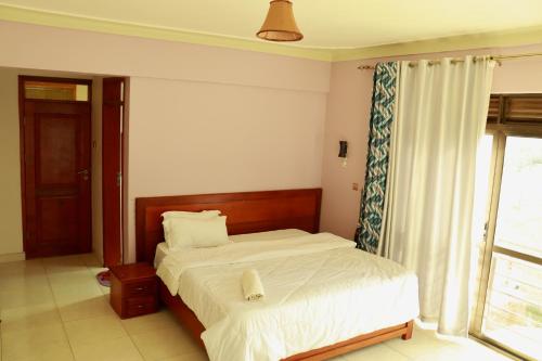un dormitorio con una cama y una ventana en Jasmine Hotel Soroti, en Soroti