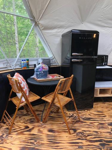 a table and two chairs and a refrigerator in a tent at Humble Hippie in Rogers