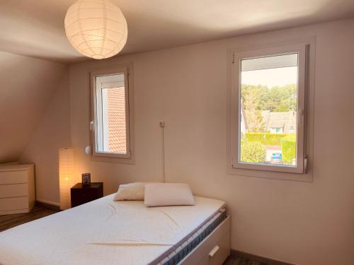 a bedroom with a bed and two windows at Le Suroit Etaples in Étaples