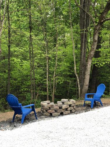 two blue chairs sitting next to a pile of logs at Humble Hippie in Rogers