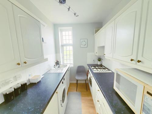 a kitchen with white cabinets and a black counter top at Luxury 1 bed apartment in East Croydon in South Norwood