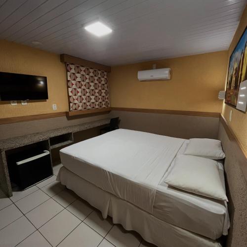 a bedroom with a bed and a flat screen tv at Hotel Veraneio in Recife