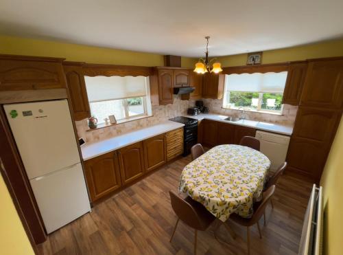 a kitchen with a table and a white refrigerator at Sunny South East Holiday Home in Clashmore