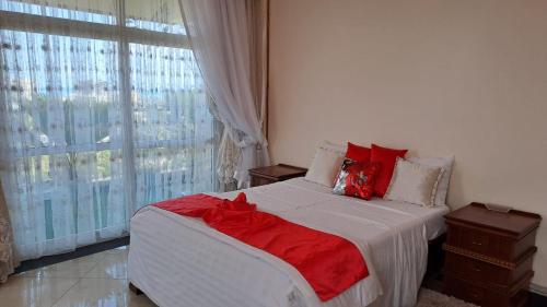 a bedroom with a bed with red pillows and a window at Nyali Emirates Reef 10C VIP 4 Bedroom Luxury Apartment with private nude sunbathing in Mombasa