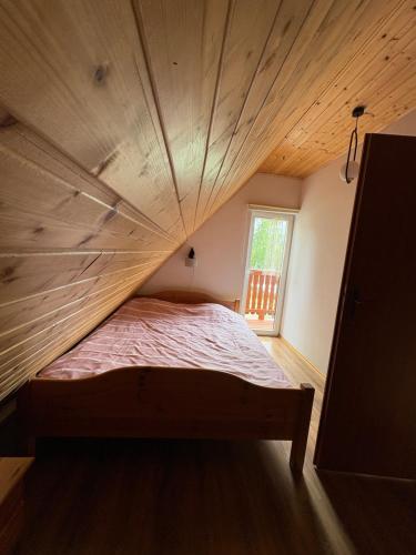 a bed in a room with a wooden ceiling at Kemping Zjawa - Polańczyk in Polańczyk
