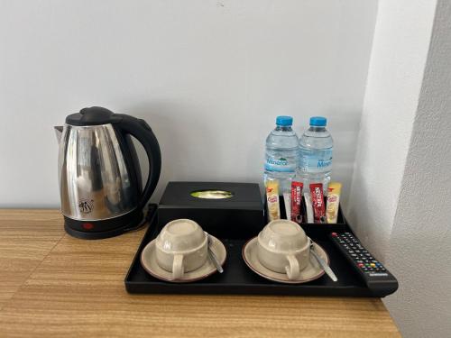 a tray with a tea kettle and two cups and water bottles at Dawn Boutique Luangprabang Hotel in Luang Prabang