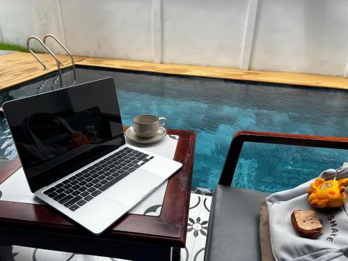 a laptop computer sitting on a table next to a swimming pool at Dawn Boutique Luangprabang Hotel in Luang Prabang