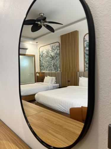 a mirror reflecting a bedroom with two beds at Dawn Boutique Luangprabang Hotel in Luang Prabang