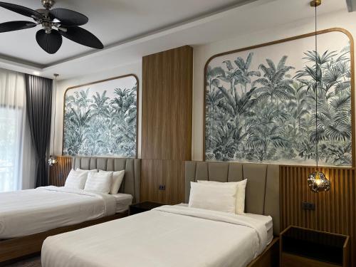 two beds in a hotel room with a painting on the wall at Dawn Boutique Luangprabang Hotel in Luang Prabang