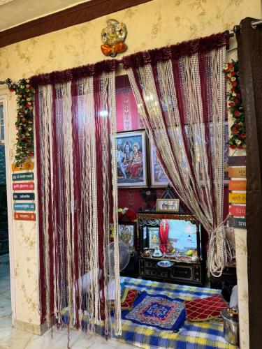 Una habitación con televisión, cortinas y una mesa. en Homestay Pathankot, en Pathankot