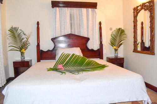 a bedroom with a white bed with a wooden headboard at Boutique B&B at Stone Village in Bluefields