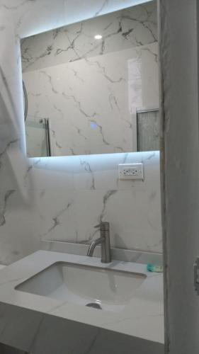 a white bathroom with a sink and a mirror at Boutique B&B at Stone Village in Bluefields