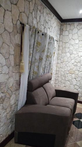 a couch in a room with a stone wall at Boutique B&B at Stone Village in Bluefields