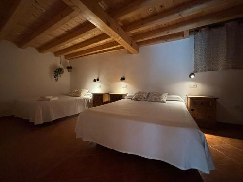 two beds in a room with wooden ceilings at Hostal El Rincon de la Vera in Losar de la Vera