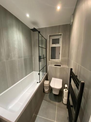 a bathroom with a bath tub and a toilet at Blue House in Stone Grove
