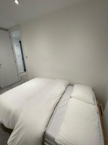 a bed with white sheets and pillows in a room at Blue House in Stone Grove