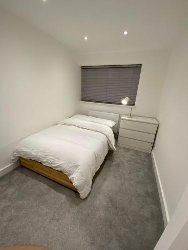 a white bedroom with two beds and a window at Blue House in Stone Grove
