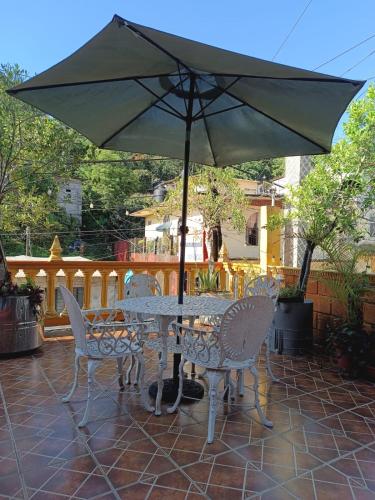 a table and chairs with an umbrella on a patio at POSAD FAMILIAR EL PARAiSO in Xilitla