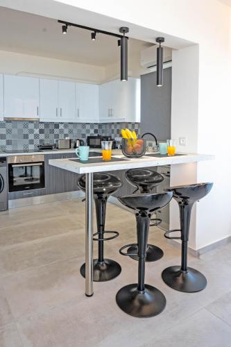 a kitchen with a large white island with bar stools at Blue Sea Benitses - Beachfront Apartment in Benitses