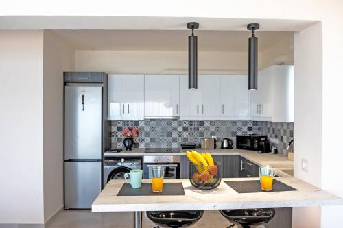 a kitchen with white cabinets and a counter with fruit on it at Blue Sea Benitses - Beachfront Apartment in Benitses