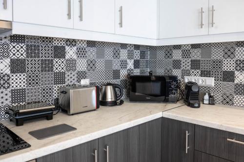 a kitchen with a black and white tiled wall at Blue Sea Benitses - Beachfront Apartment in Benitses