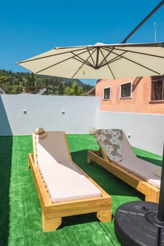 a bed and an umbrella on the grass at Blue Sea Benitses - Beachfront Apartment in Benitses