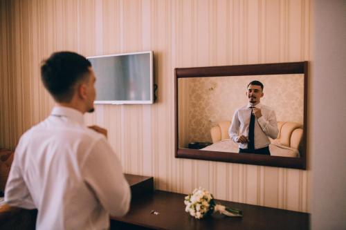 a man standing in front of a mirror in a hotel room at Globus Hotel in Ternopilʼ